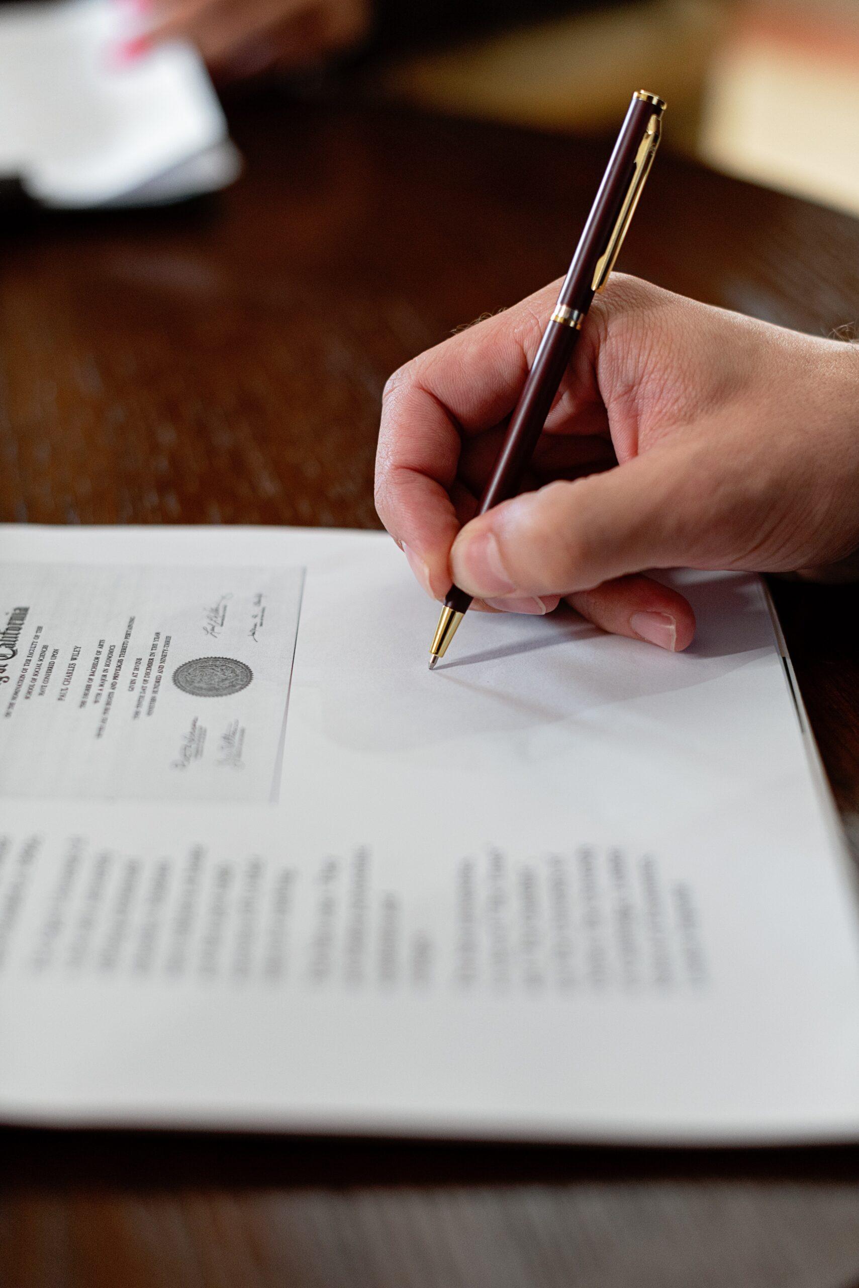 a pen holding hand signing on a document